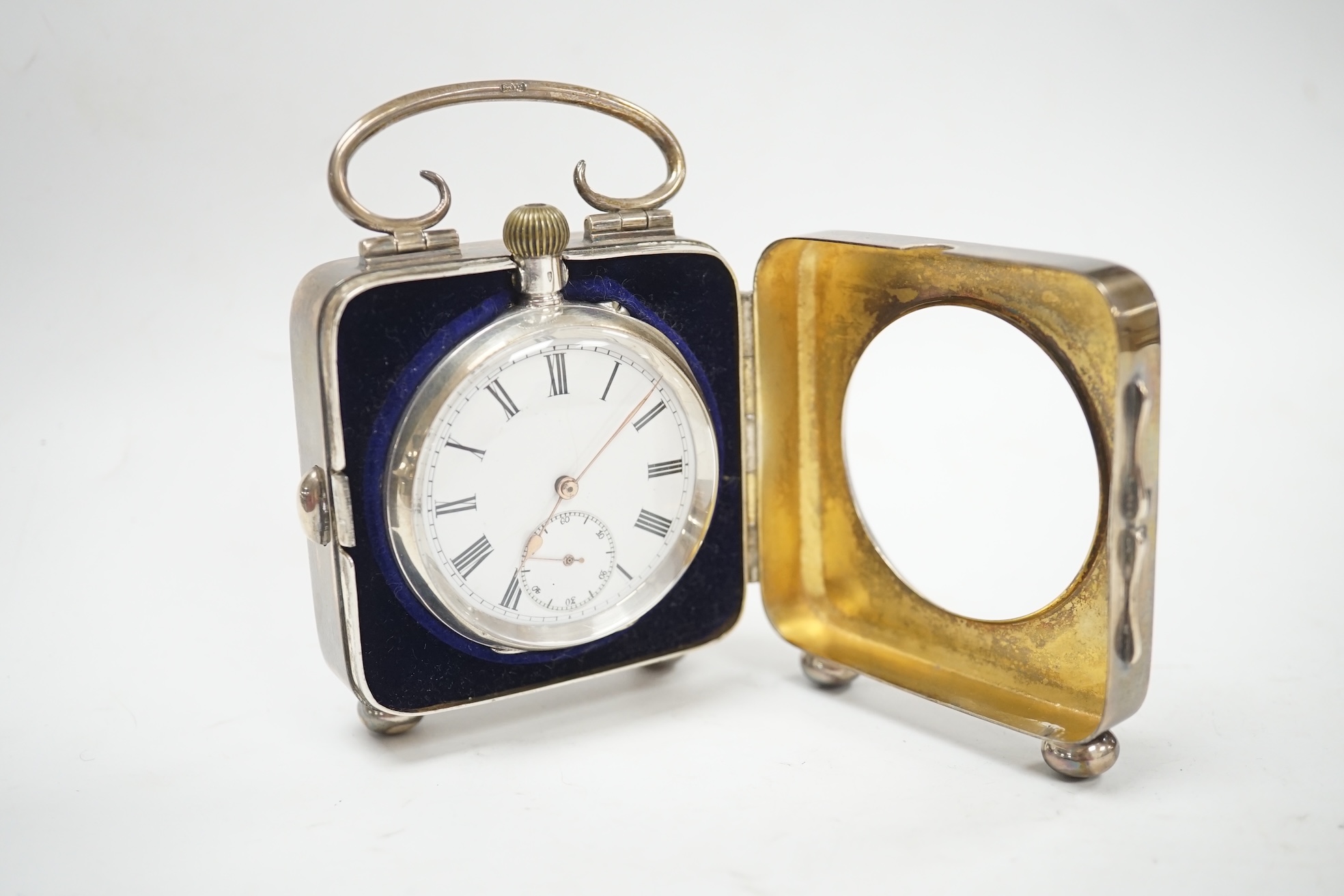 An Edwardian silver travelling pocket watch case, Birmingham, 1904, on bun feet, containing a Swiss white metal open face pocket watch. Condition - fair